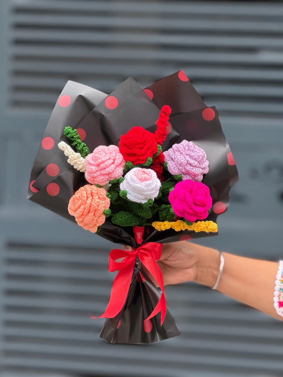 Crochet rose bouquet in pink, red and lilac wrapped in black polka dot paper