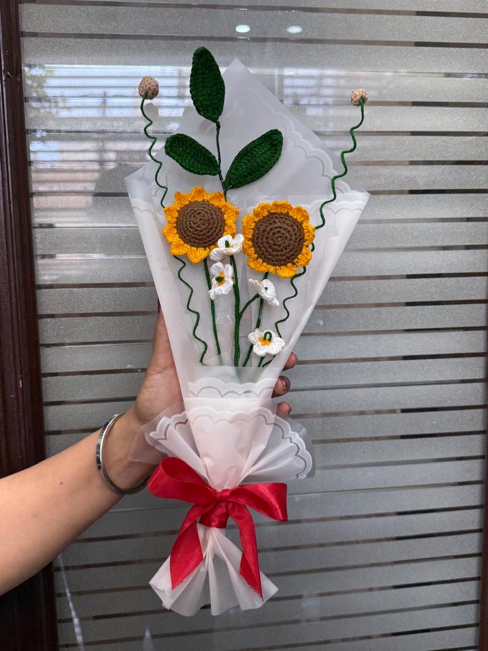 Crochet sunflower bouquet with white daisies wrapped in white paper with a red bow