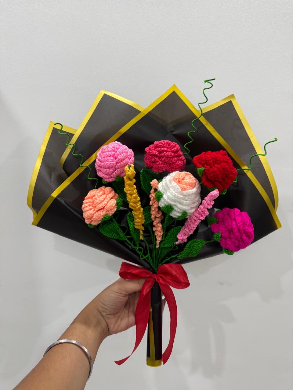 Crochet rose bouquet in coral, pink and red wrapped in black and yellow paper